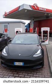 Wichrow, Poland - January 14, 2022. A static shot of a solid black Tesla Model 3 dual motor long range awd charging at the Supercharger during winter. Selective focus.