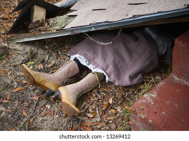 Wicked witch of the west (from the Wizard of Oz) sticking out from under house destroyed by a tornado.
