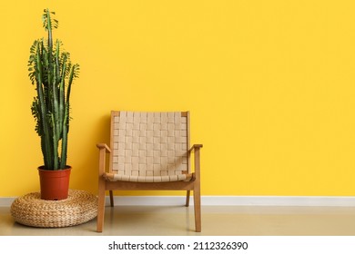 Wicker Armchair With Houseplant On Ottoman Near Yellow Wall