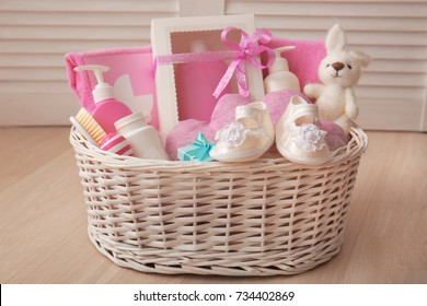 Wicker Basket With Baby Shower Gifts On Floor Indoors