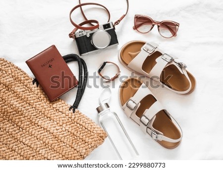 Wicker basket, camera, passport, leather sandals - travel concept on a light background, top view      