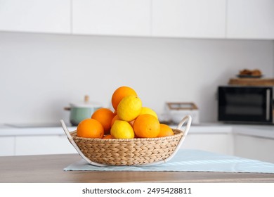 Wicker basket with citruses on table in white kitchen