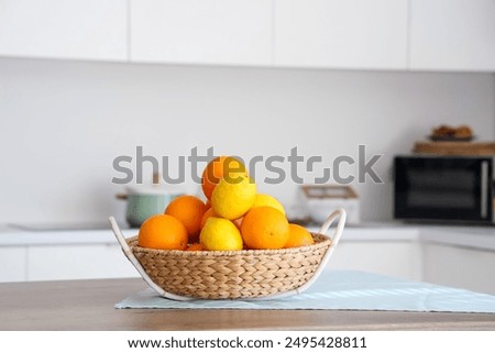 Wicker basket with citruses on table in white kitchen