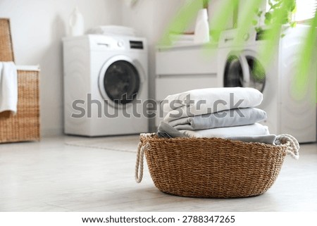 Wicker basket with clean bed sheets on floor in bathroom