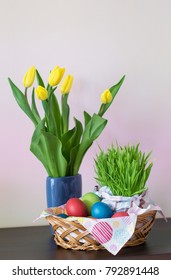 A wicker basket with colorful Easter eggs, yellow tulips in vase, Easter decoration on light background. Free space for yourt text. - Shutterstock ID 792891448