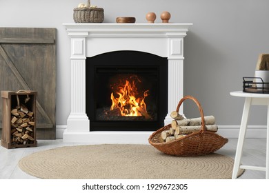 Wicker basket and crate with firewood near white fireplace in cozy living room