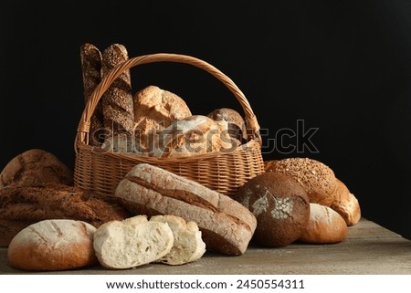Wicker basket with different types of fresh bread on wooden table