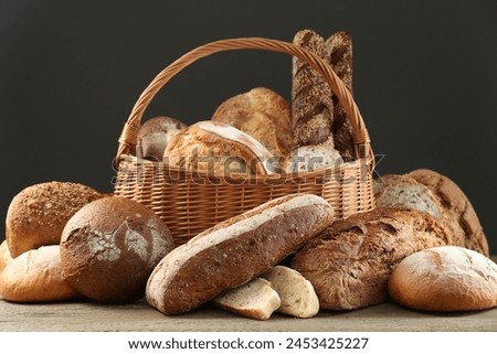 Wicker basket with different types of fresh bread on wooden table