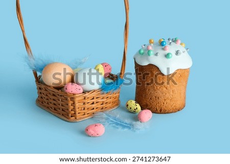 Wicker basket, Easter eggs and cake on blue background