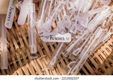 Wicker basket filled with miniature bubble wands and blowers labeled with the inscription “Forever”, party favours for guests to use as bride and groom leave church on wedding day - Shutterstock ID 2213502337