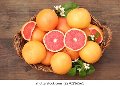 Wicker basket with fresh grapefruits and green leaves on wooden table, top view - Powered by Shutterstock