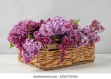 Wicker basket with fresh lilac flowers on light  table - Powered by Shutterstock