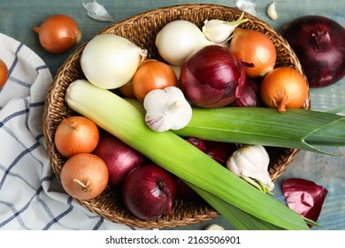 Wicker basket with fresh onion bulbs, leeks and garlic on light blue wooden table, flat lay - Powered by Shutterstock