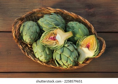 Wicker basket with fresh raw artichokes on wooden table, top view - Powered by Shutterstock
