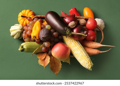 Wicker basket with fresh vegetables, fruits and autumn leaves on green background. Harvest festival - Powered by Shutterstock