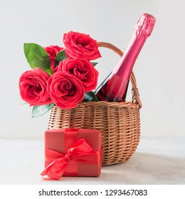 Wicker Basket With Gift, Bouquet Of Red Roses, Sparkling Wine On White. Gift Baskets And Flower Deliveries. Close Up. Hamper Ultimate Gift.