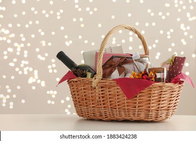Wicker basket with gifts, wine and food against blurred festive lights. Space for text - Shutterstock ID 1883424238