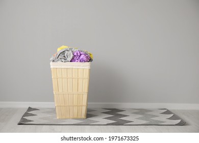 Wicker Basket With Laundry Near Light Wall