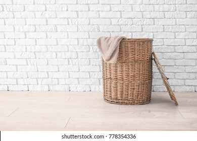 Wicker Basket With Laundry On Floor Against Brick Wall