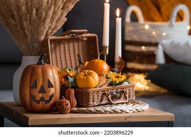 A wicker basket with pumpkins, Jack's Pumpkin and candles in the interior of the living room on a wooden table. The concept of home comfort. Autumn decor for Halloween. - Shutterstock ID 2203896229