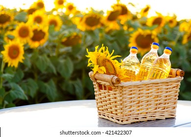 Wicker basket with sunflower and three bottles of oil on the background of the field