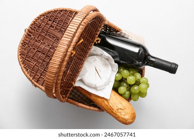 Wicker basket with tasty food and drink for picnic on white background. Top view - Powered by Shutterstock