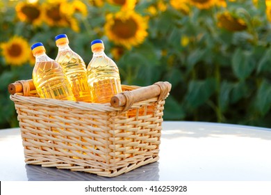 Wicker basket with three bottles of sunflower oil on the background of the field.Backlight.