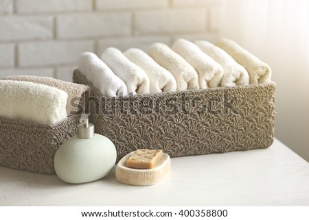 Wicker basket with towels inside and soap on wooden table background