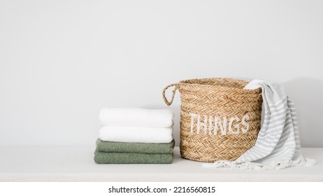 wicker basket with unwashed linen bedding and fresh bath towels tidy folded on surface on white background with copy space, laundry concept