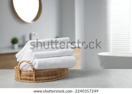 Wicker basket with white towels on table in bathroom. Space for text