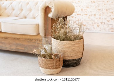 Wicker baskets with dried flowersnear the sofa on floor. Living room hygge, autumn cozy home decor. Scandinavian interior. Comfortable bedroom in bohemian interior style. Rustic. dry plants in vase