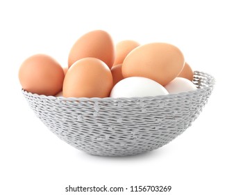 Wicker bowl with chicken eggs on white background