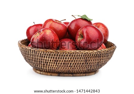 Wicker bowl of ripe juicy red apples with leaf on white background
