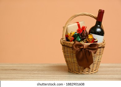 Wicker Gift Basket With Food And Wine On Wooden Table. Space For Text