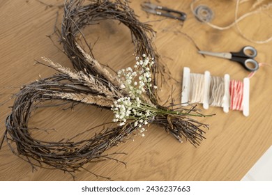 Wicker heart shaped wreath of birch branches and supplies for DIY making on wooden table background. Wreath weaving, crafting, handmade decoration - Powered by Shutterstock