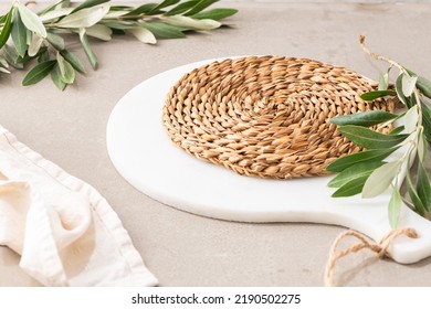 Wicker Mat And Marble Cutting Board On White Moody And Modern Kitchen Countertop Decorated With Olive Leaves And Towel. Concept