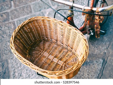 Wicker Old Bicycle Basket. Vintage Bike On The Street As Background. Top View To The Cobblestone