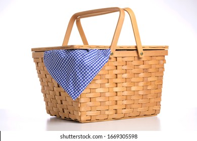 Wicker picnic basket on a white background with blue gingham tablecloth