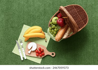 Wicker picnic basket with tasty food on green grass background - Powered by Shutterstock