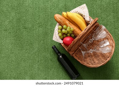 Wicker picnic basket with tasty food, glasses and bottle of wine on green grass background - Powered by Shutterstock