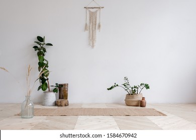 Wicker rug is lying on wooden floor next to pots with plants and hanging on the wall with wicker macrame on a white background. Concept is a cozy place in the house for classes. Advertising space - Powered by Shutterstock