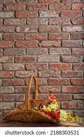 Wicker Trug Gathering Basket Filled With Silk Flowers Standing On Red Brick Fireplace Hearth With Copy Space