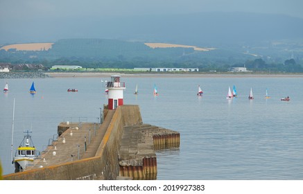 Wicklow Lighthouse With Many Sailboats On The Irish Seaside.