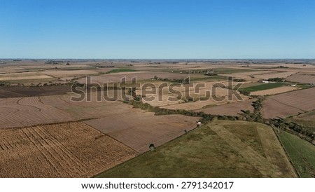Wide aerial drone shot of patchwork agricultural fields and farmlands under a clear blue sky in Entre Rios, Argentina.