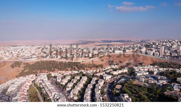 Wide Aerial footage of Israel\
and Palestine town divided by fence with Judean desert mountains \
