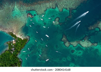 wide aerial shot of many boats out on the water in beautiful green blue water