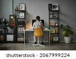 Wide angle back view at man using computer at home office with modern tech interior, copy space