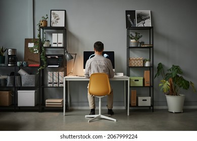 Wide angle back view at man using computer at home office with modern tech interior, copy space - Powered by Shutterstock
