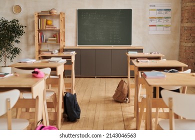 Wide angle background image of wooden school desks in row facing blackboard in empty classroom, copy space