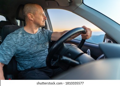 Wide Angle Closeup Of A Man Driving His Car And Watching Sunrise On The Window